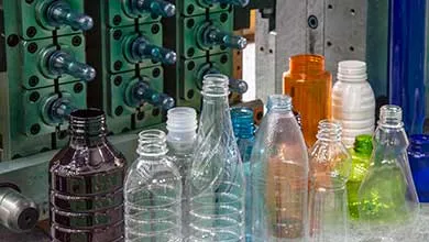 The plastic bottles and injection mold in background. PET plastic bottle manufacturing concept.